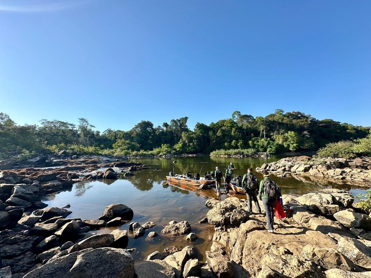 A rocky stretch at low water, with a boat moored and gear carried over the boulders